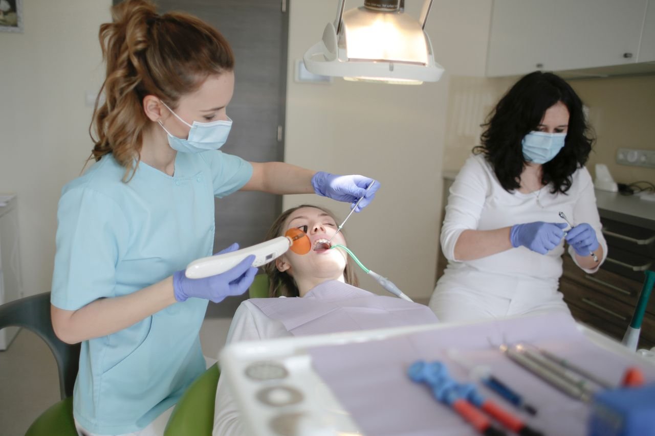 A dentist and nurse in a clinic working on a patient's dental care with advanced tools.